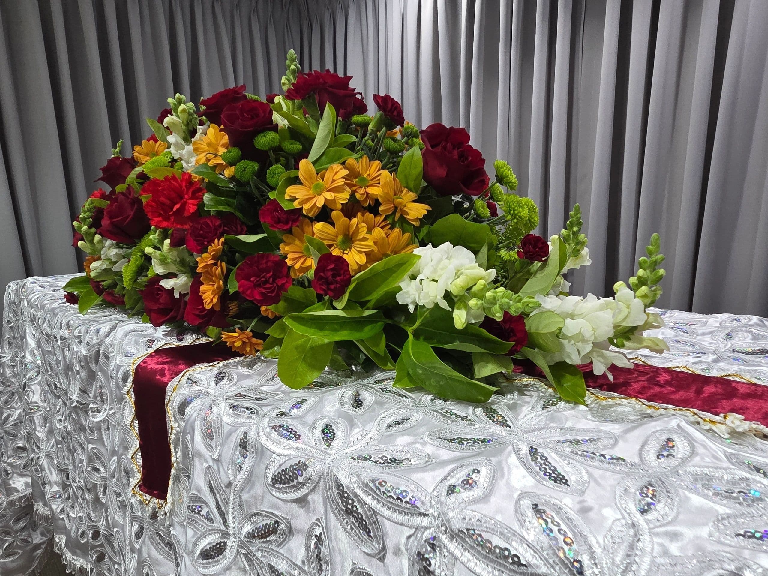 A vibrant floral arrangement on a decorative, sequined cloth-covered table.