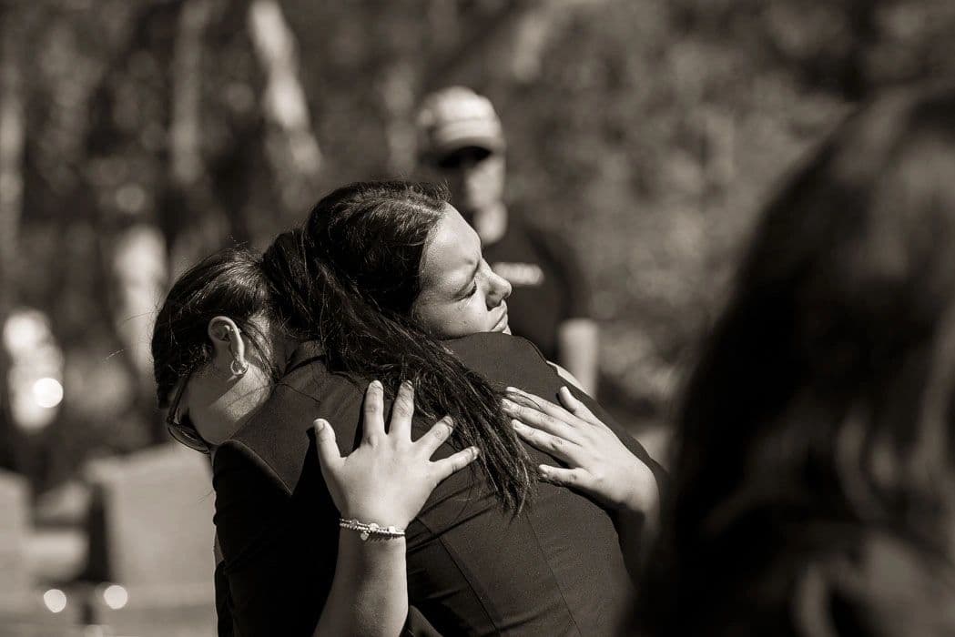 Two women sharing a heartfelt embrace outdoors.