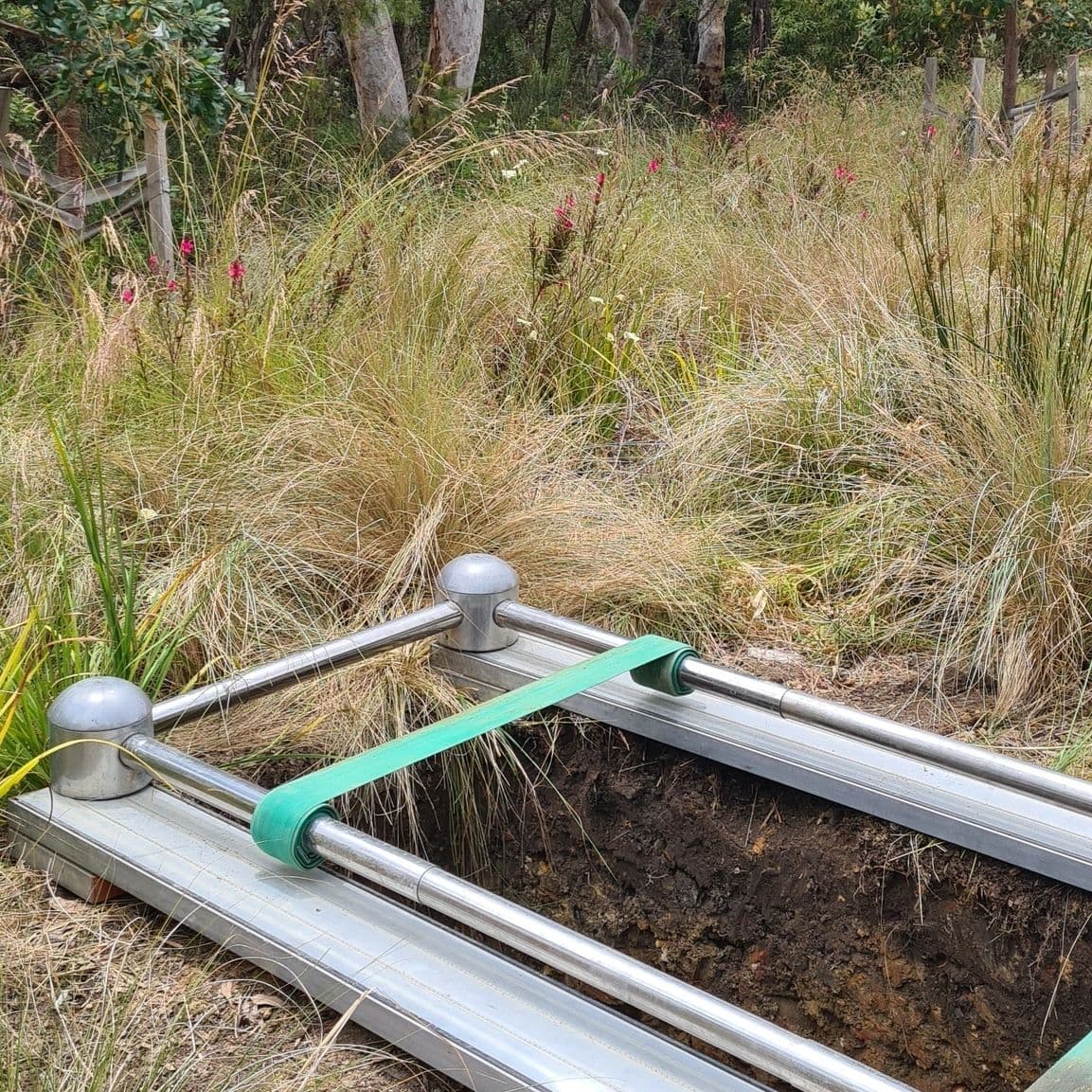 A soil sampling device set up in a grassy field for environmental study.