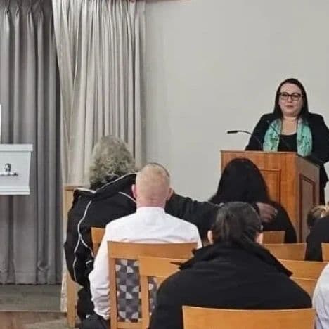 Woman speaking at a podium in front of an audience.